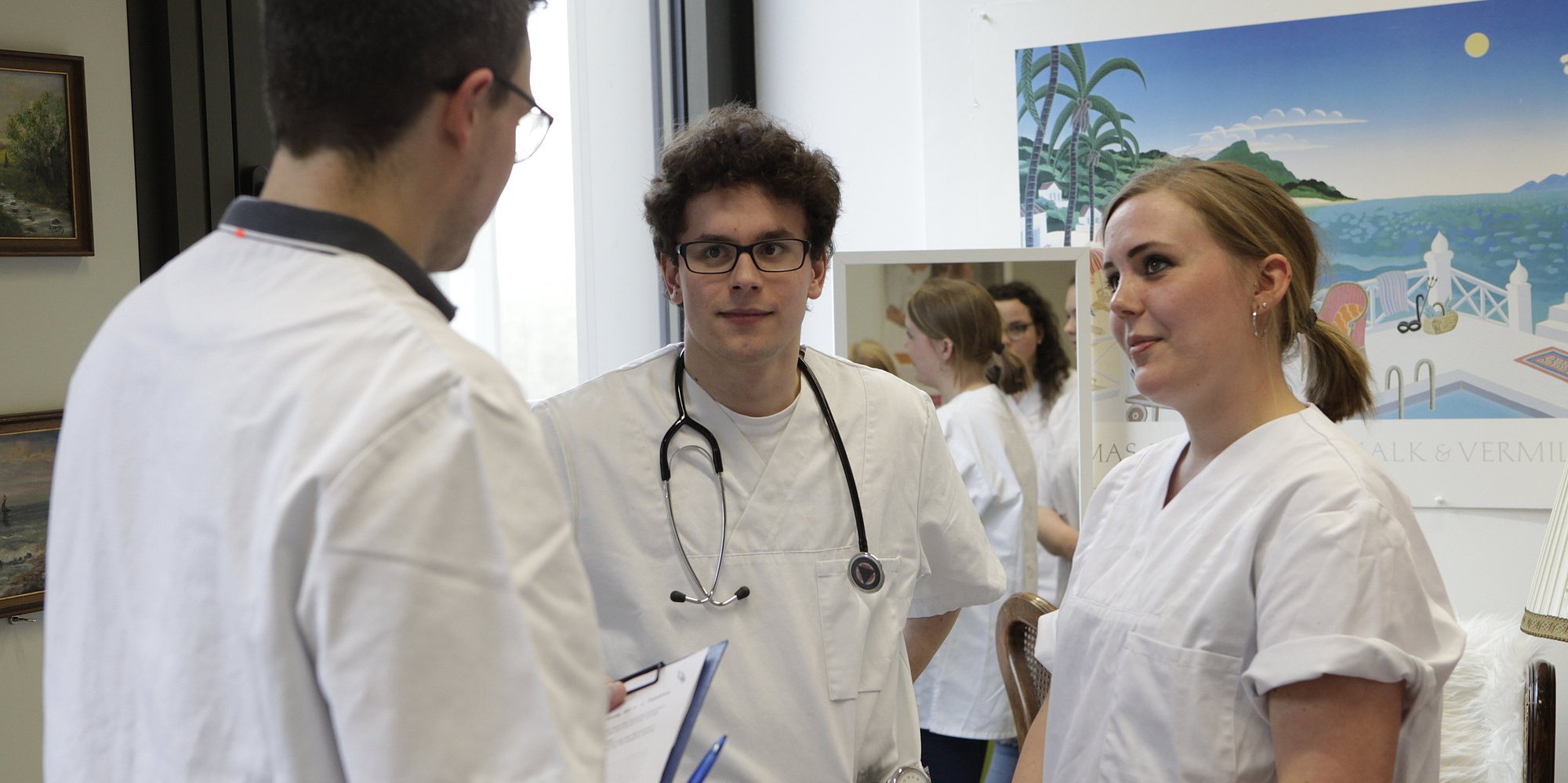 Drei Personen in weißen Kitteln unterhalten sich.