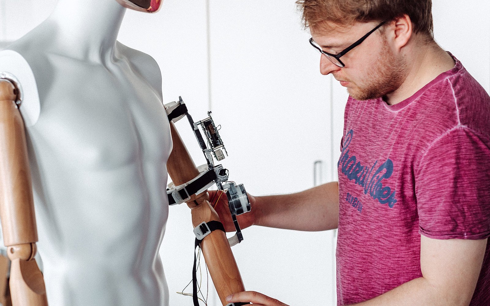 Eine Person schließt technische Geräte an eine menschliche Puppe an.